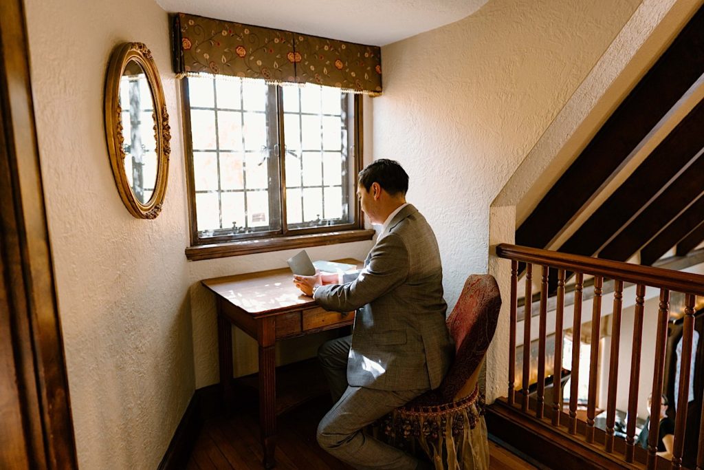 A groom writes his vows in the getting ready space of the Grove Redfield Estate.