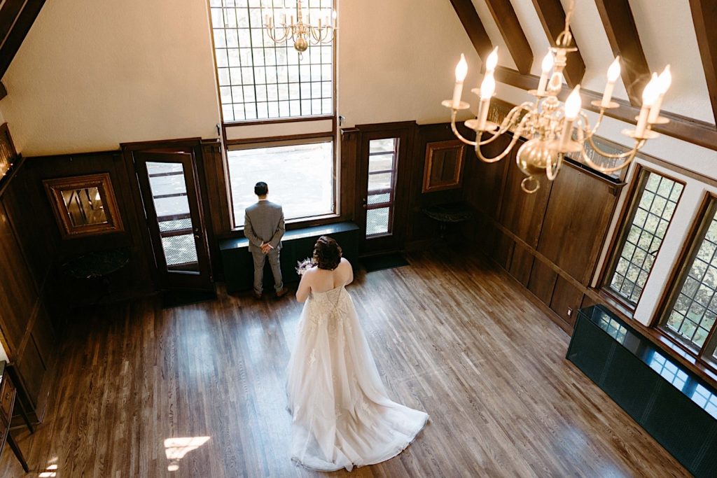 A bride and groom share a first look in the main room of the Grove Redfield Estate.