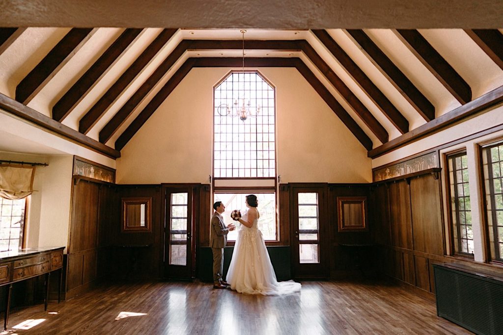 A bride and groom share a first look in the main room of the Grove Redfield Estate.