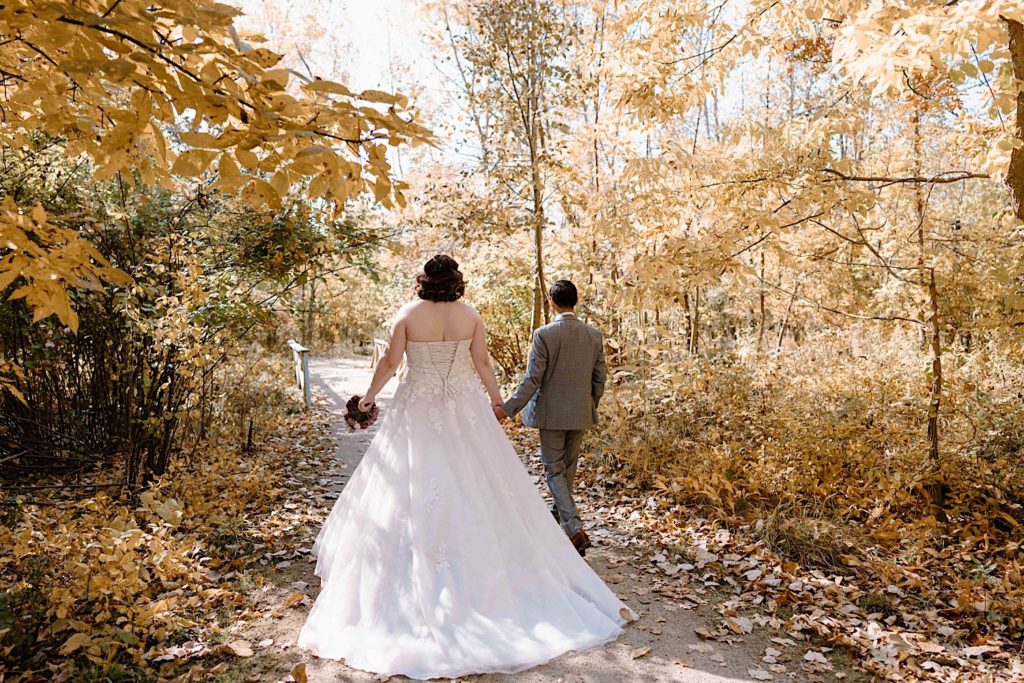 A bride and groom walk through the Grove Redfield Estate in the fall after their elopement ceremony.