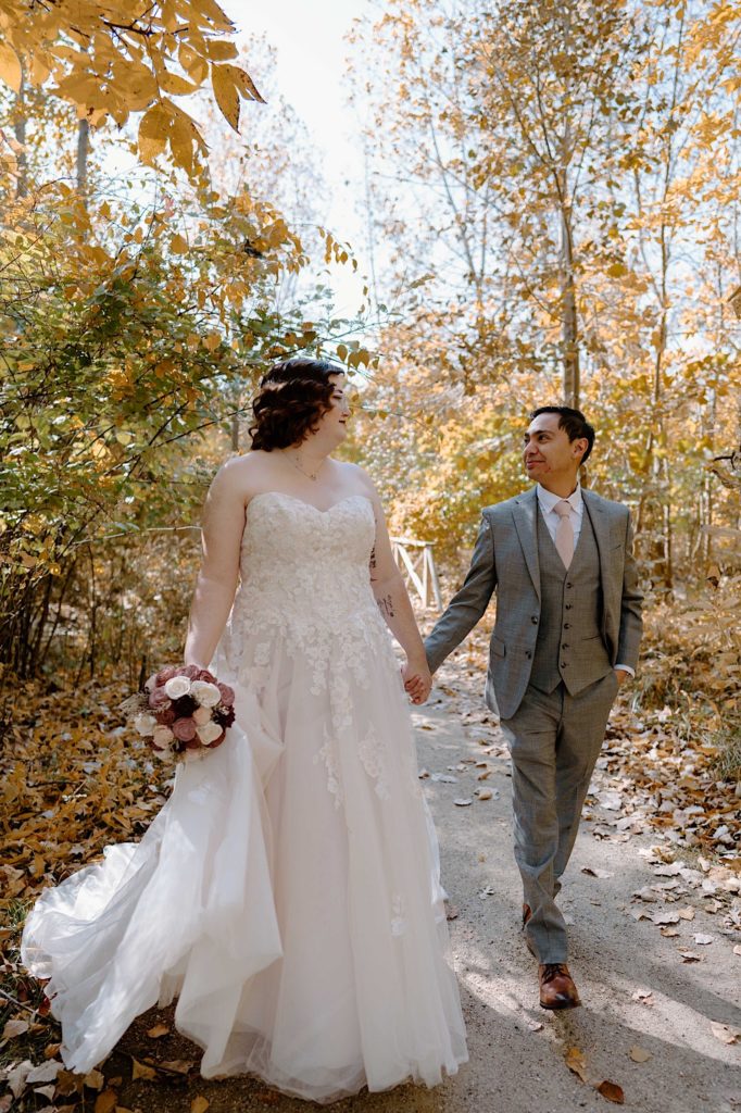 A bride and groom walk through the Grove Redfield Estate in the fall after their elopement ceremony.
