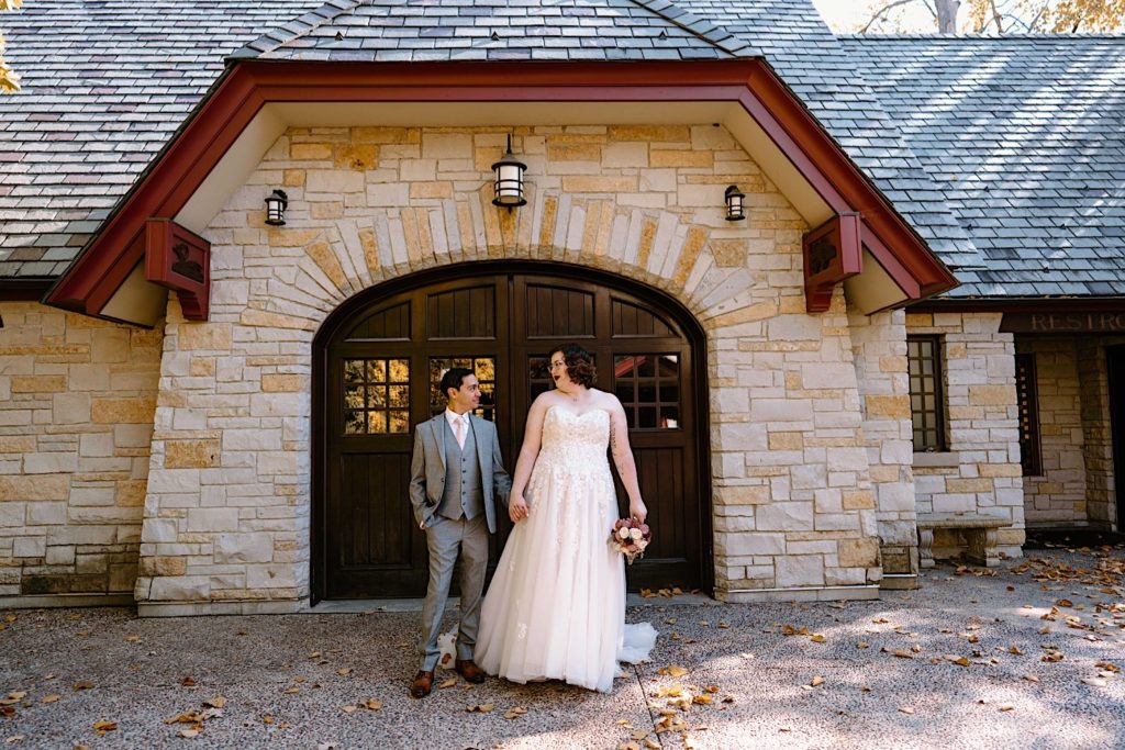 A bride and groom stand in front of the Grove Redfield Estate in the fall after their elopement ceremony.