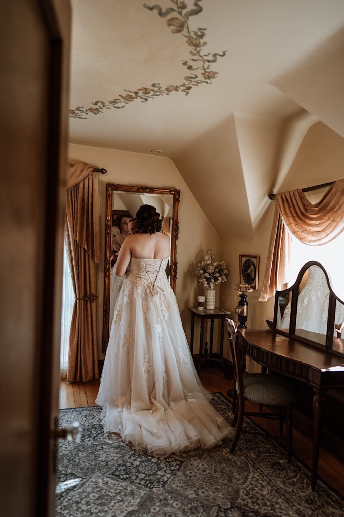 A bride stands in the getting ready room at Grove Redfield Estate 