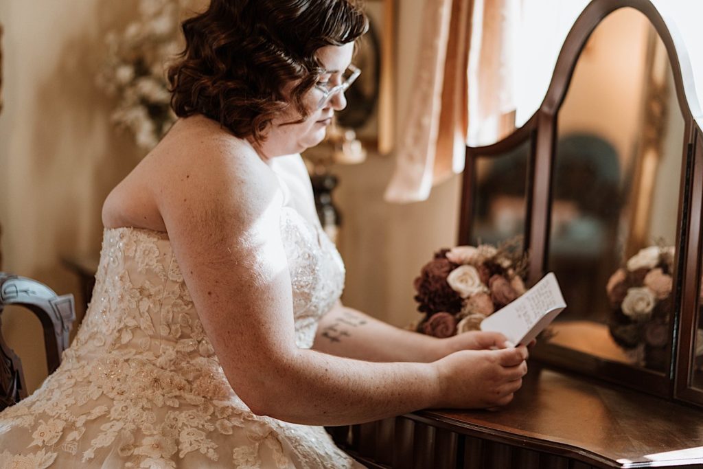A bride sits reading her vows in the getting ready room at Grove Redfield Estate 