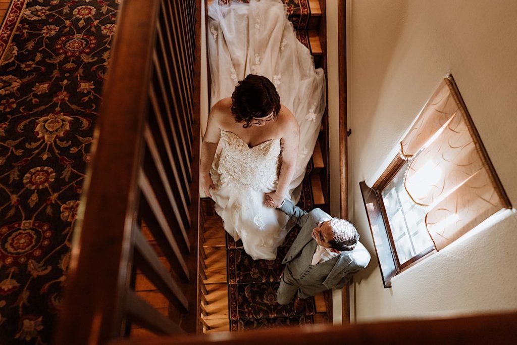 A bride and groom hold hands walking down the stairs after their elopement at the Grove Redfield Estate