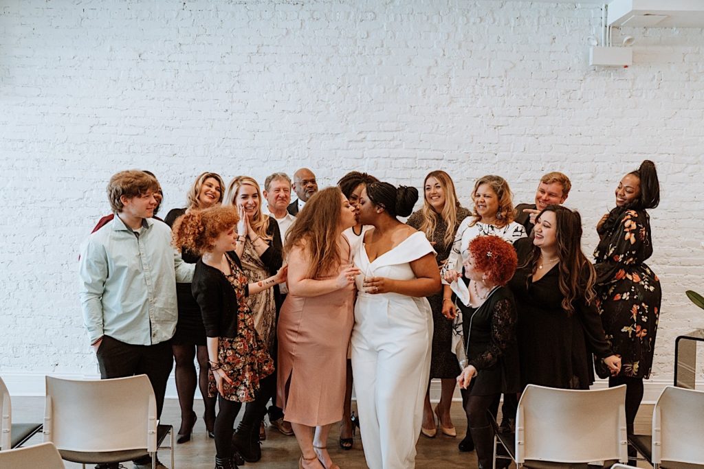 Brides kiss one another surrounded by their guests at their Chicago intimate wedding.