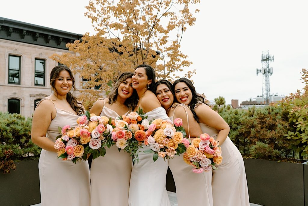 A bride and her bridesmaids smile during their wedding portraits.