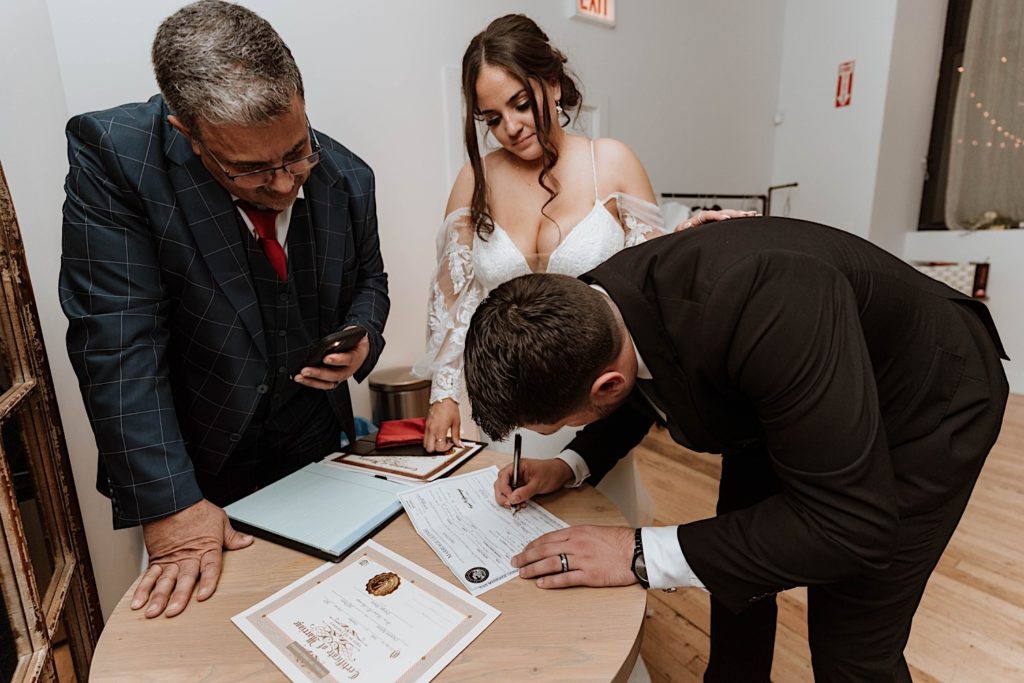 A bride and groom sign their marriage license after their ceremony.