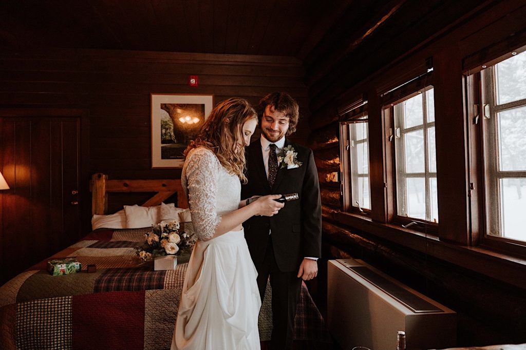 A bride and groom open up a small bottle of champagne in their cabin at Starved Rock.