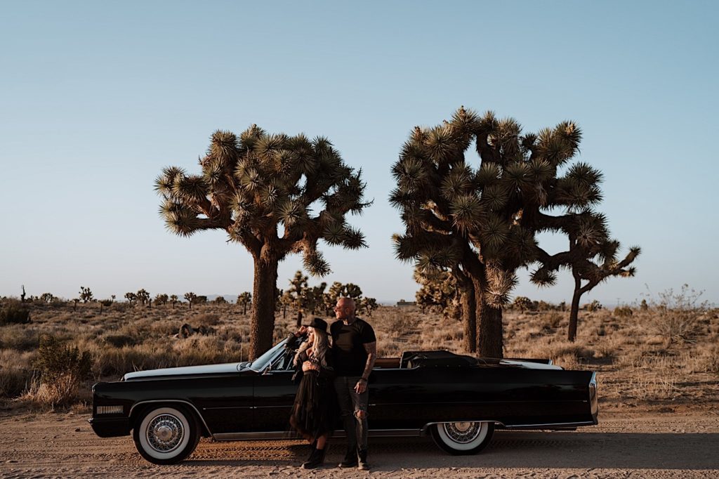 A bride and groom stand together next to a car in the desert during their Utah elopement.