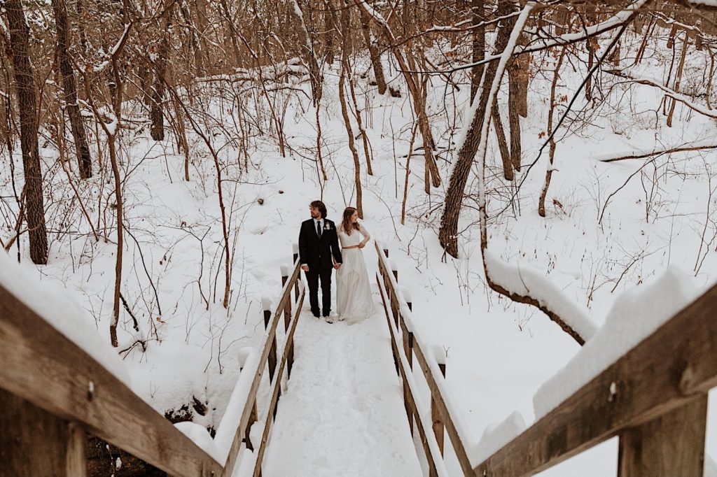 A bride and groom snuggle in close while standing on a bridge in Starved Rock National Park.