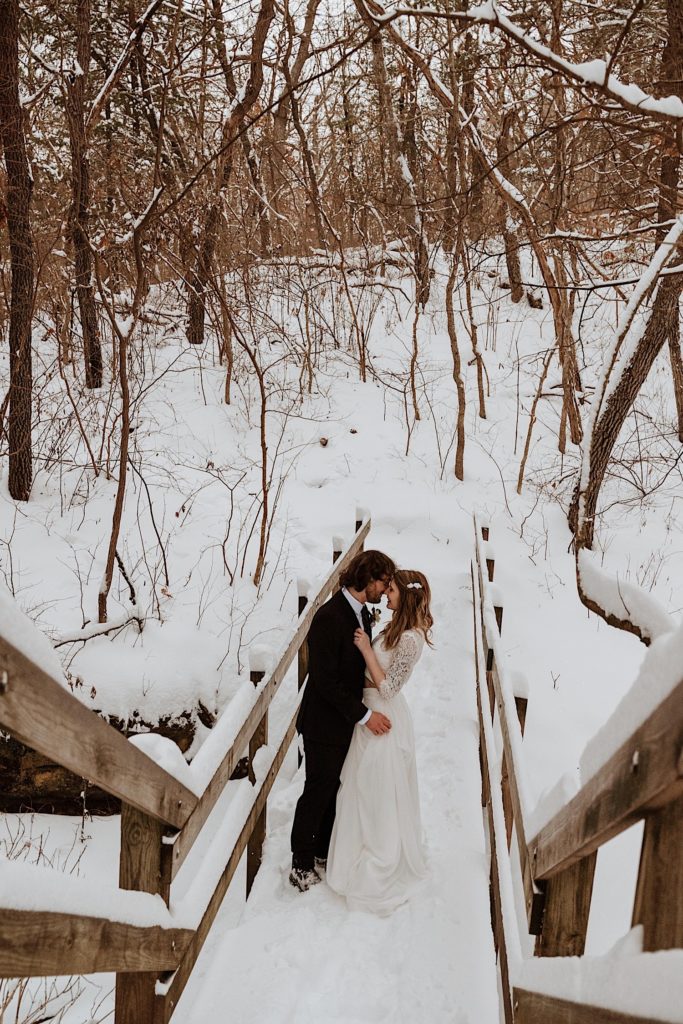 A married couple holds one another on a bridge while taking their wedding portraits at Starved Rock National Park