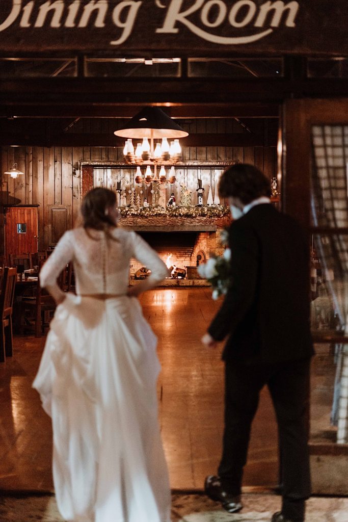 A bride and groom walk into their cabin towards the fire to warm up after taking their wedding portraits at Starved Rock National Park.