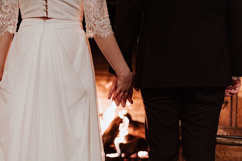 A bride and groom hold hands standing in front of the fireplace after taking their wedding portraits at Starved Rock National Park.