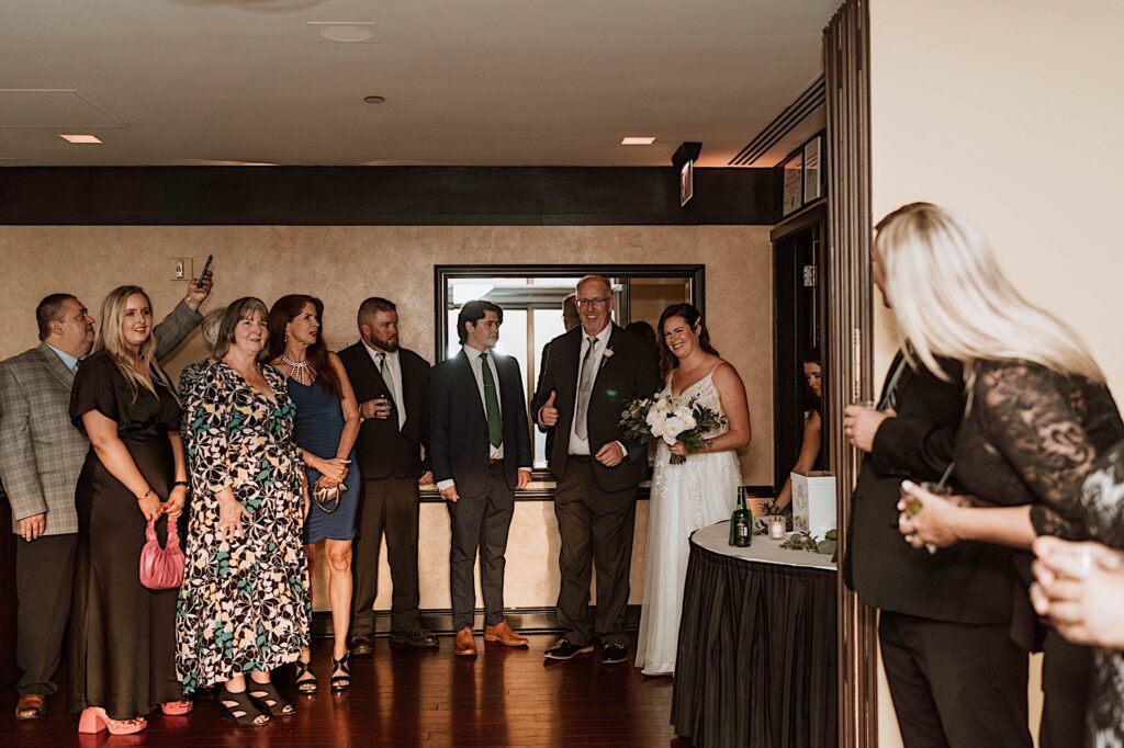 A bride walks in with her father to her wedding ceremony surrounded by friends and family at the signature room on the 95th floor.