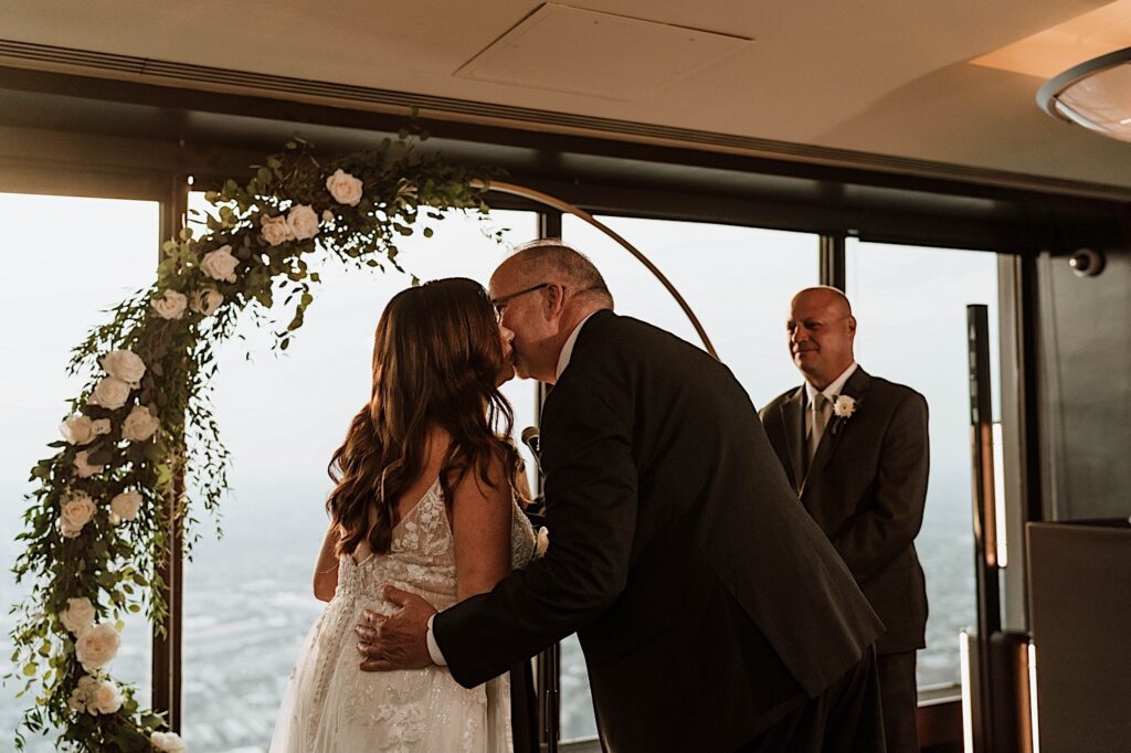 A bride kisses her father before marrying her husband at their ceremony on the 95th floor.