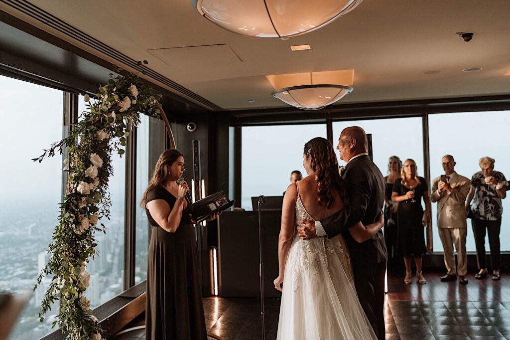 A bride and groom look at their officiant during their ceremony at their intimate Chicago wedding in a skyscraper.