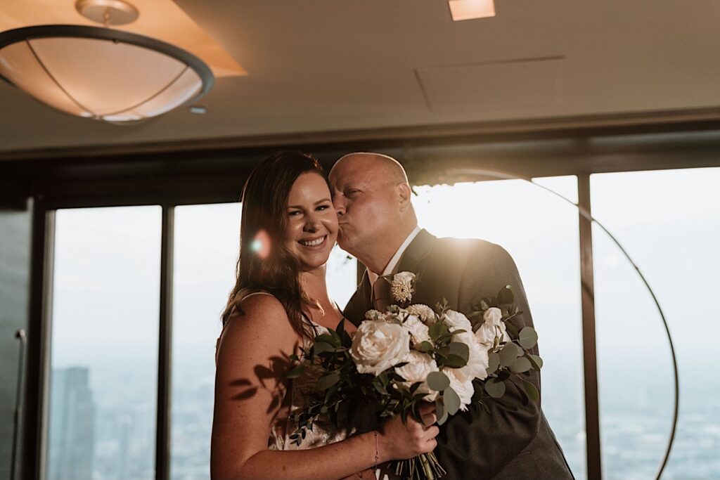 A bride and groom kiss during their wedding ceremony overlooking the city of Chicago in the Signature Room on the 95th floor.