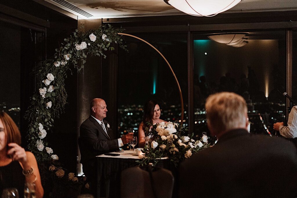 A bride and groom sit during their dinner at their wedding reception on the 95th Floor in the John Hancock Building.