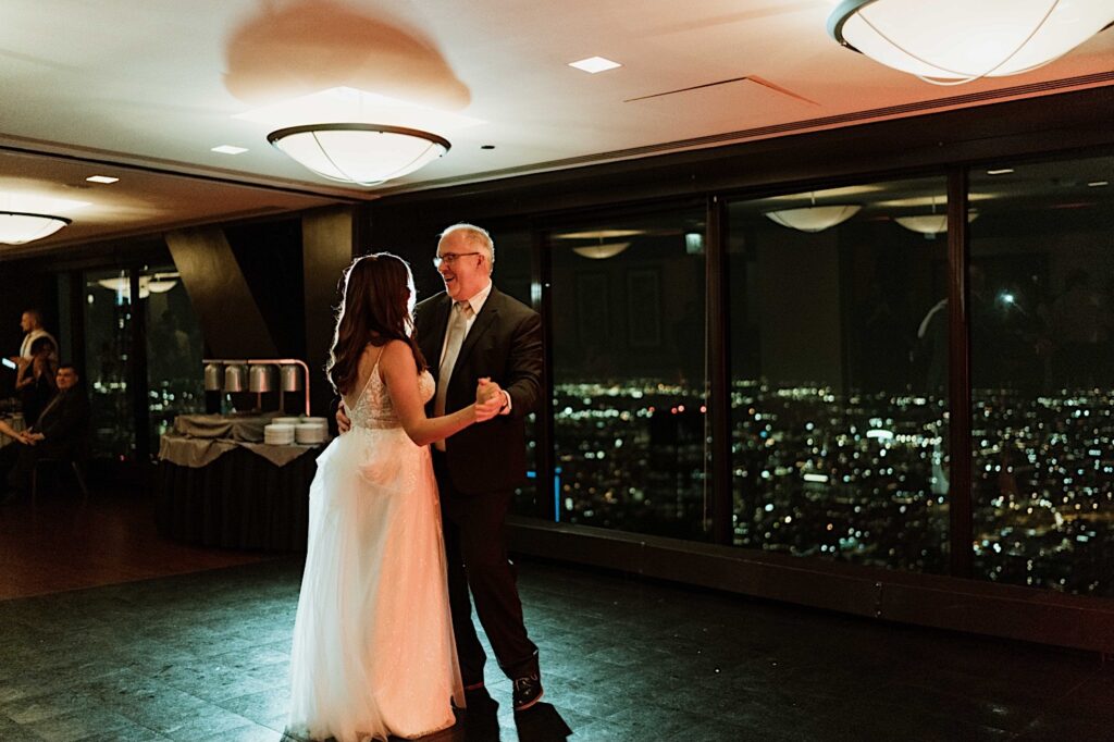 A bride and her father have their first dance at the Signature Room on the 95th floor.