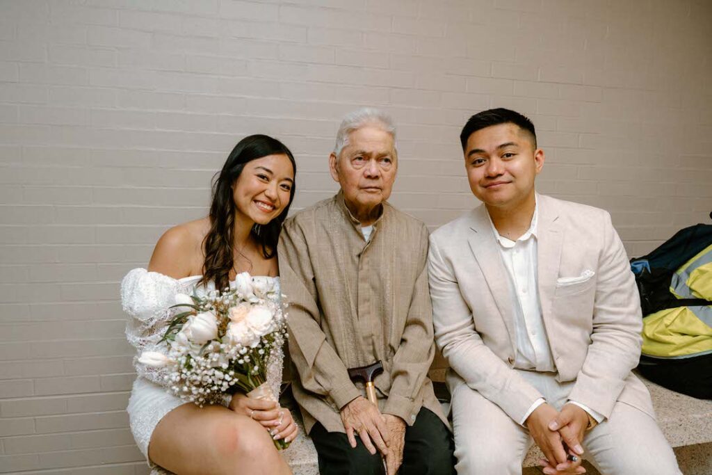 bride and groom sitting with grandpa in between them