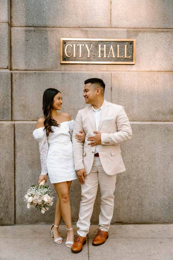 bride and groom standing under city hall sign - chicago city hall elopement