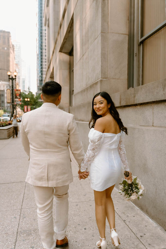 bride looking back while walking forward with her husband - chicago city hall elopement