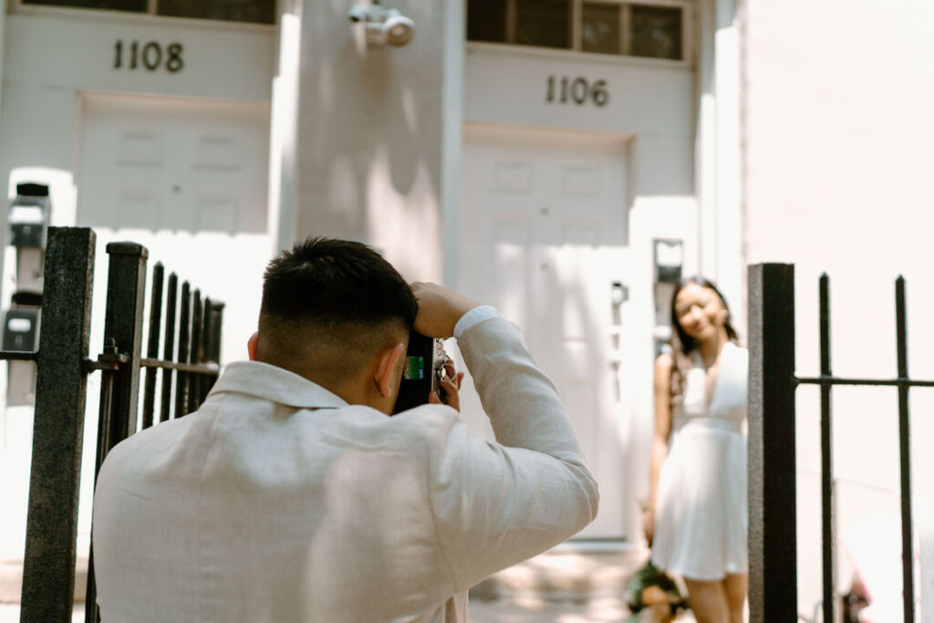 man taking a photo of his wife in front of their apartment 