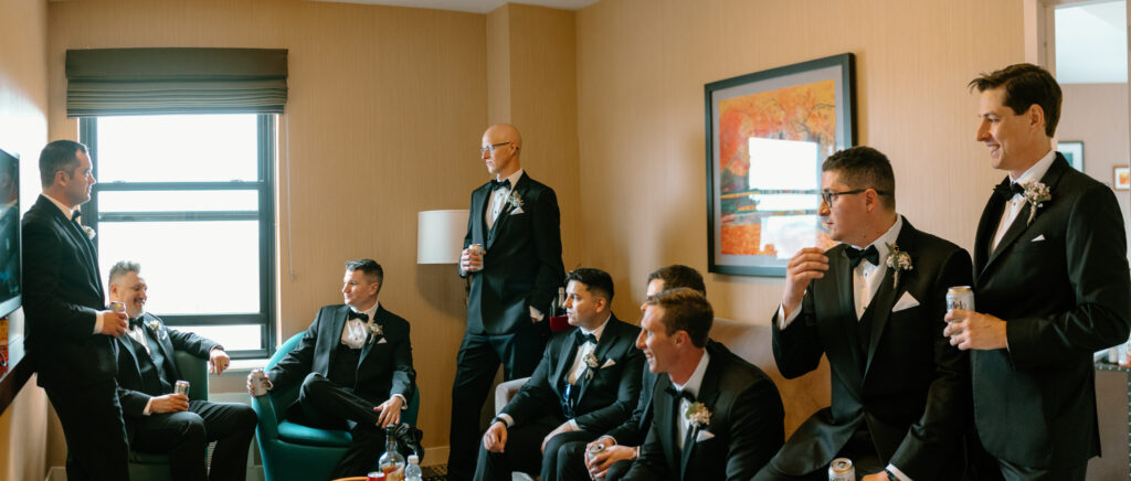 groom and groomsmen hanging out in their hotel room and drinking beer