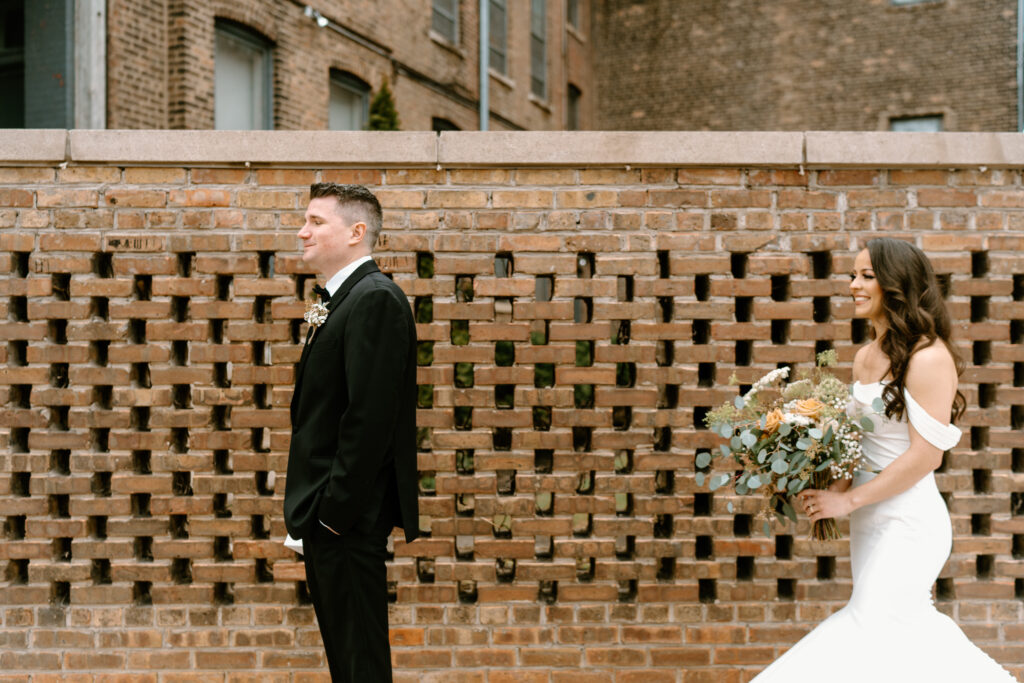 bride standing behind the groom about to surprise him for their first looks