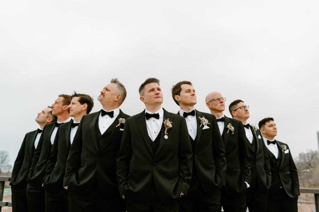 groom and his groomsmen in the flying v formation looking away at the distance to show their side profiles