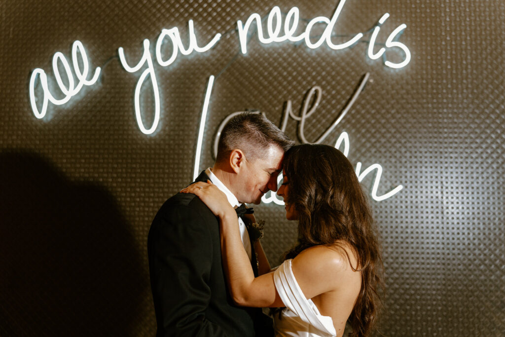 bride and groom touching foreheads as she wraps her hand around his shoulders; background says "all you need is love"