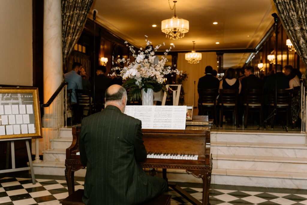 man with his back against the camera while playing the piano for the ceremony