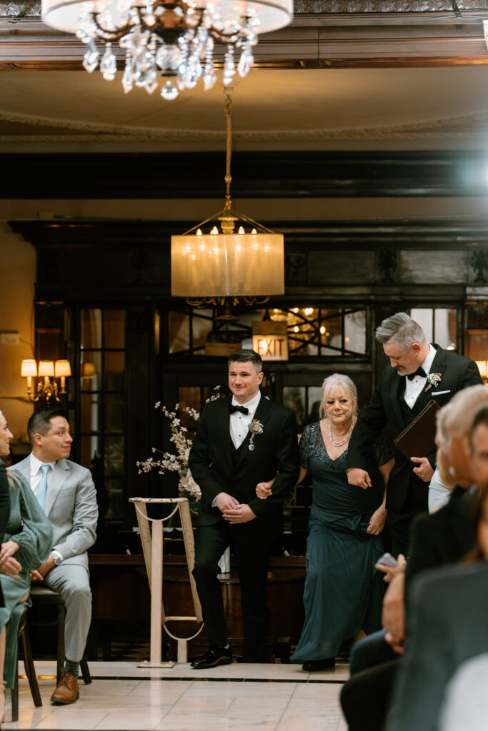 groom walking down the aisle with his mom