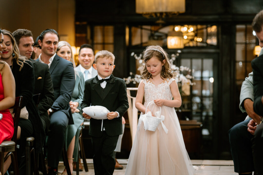 two kids; ring bearer and a flower girl walking down the aisle