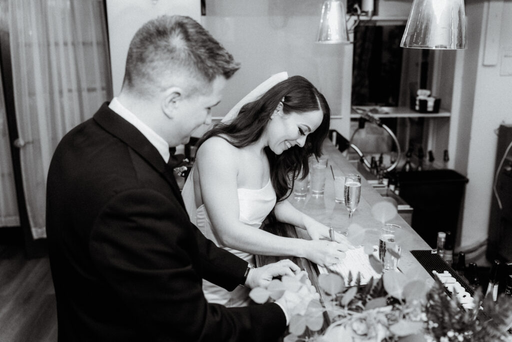 newlyweds signing their marriage license at the bar